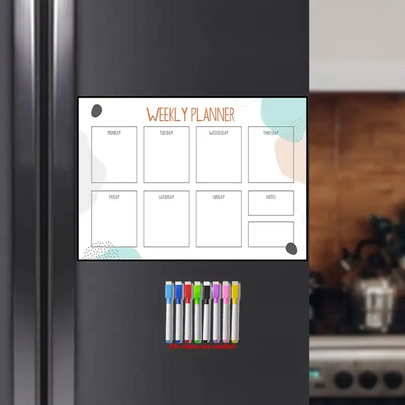 Tableau magnétique hebdomadaire pour enfant accroché au réfrigérateur avec marqueurs colorés.